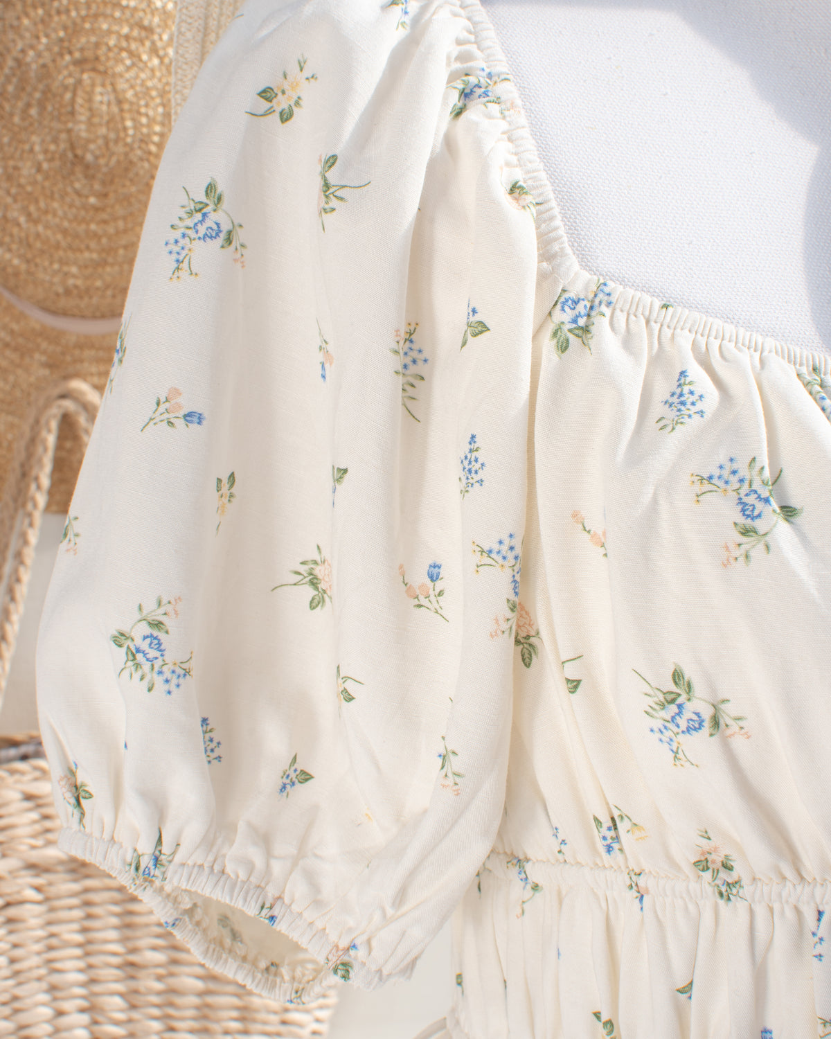 Close-up of the puff sleeve and gathered square neckline on the cream floral dress, with an elastic cuff.