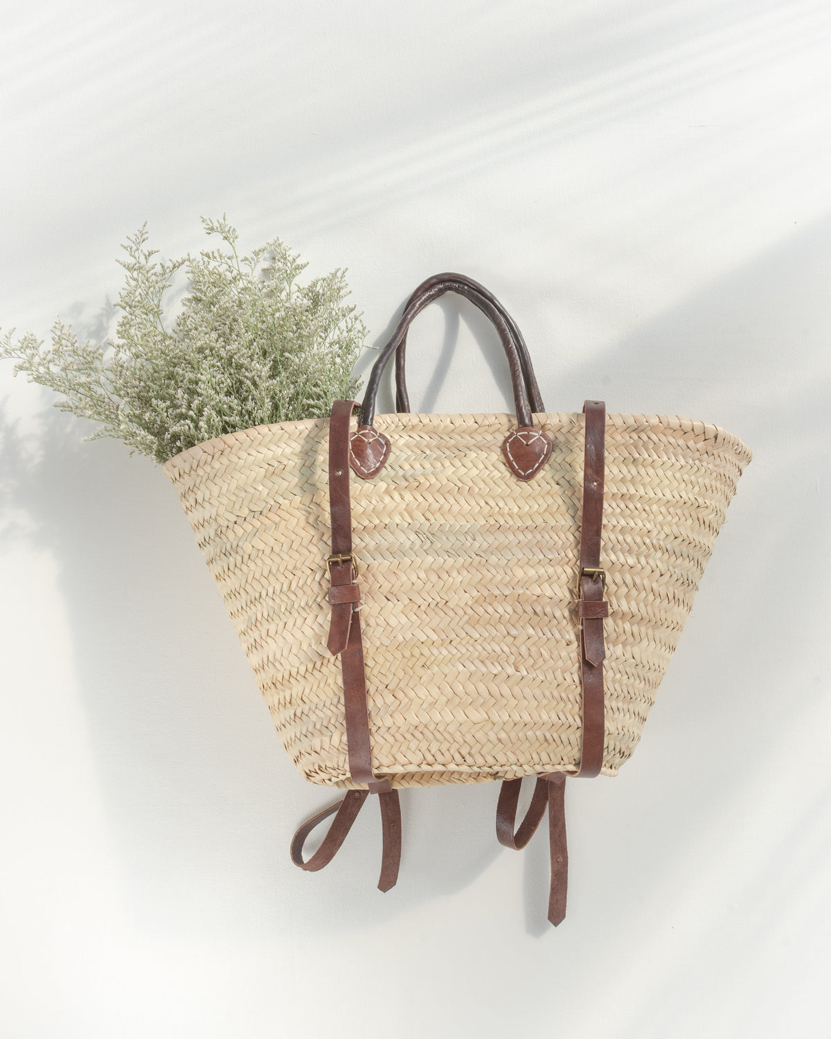 Marché backpack tote, a Provençal-style woven straw basket with rolled brown handles and backpack straps.