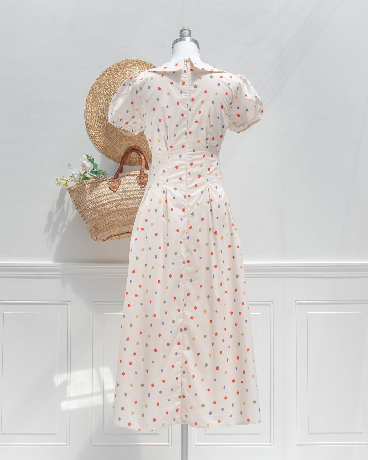 Back view of the cream polka dot dress, with a center back zipper, nipped waist and flared skirt.