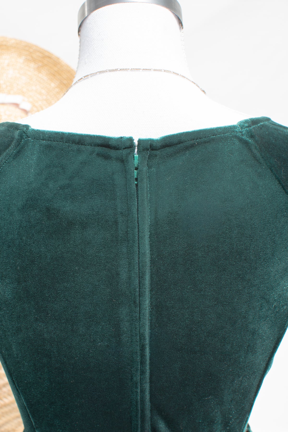 Back view close-up of the emerald velvet dress, showing the center back zipper and scooped back neckline.