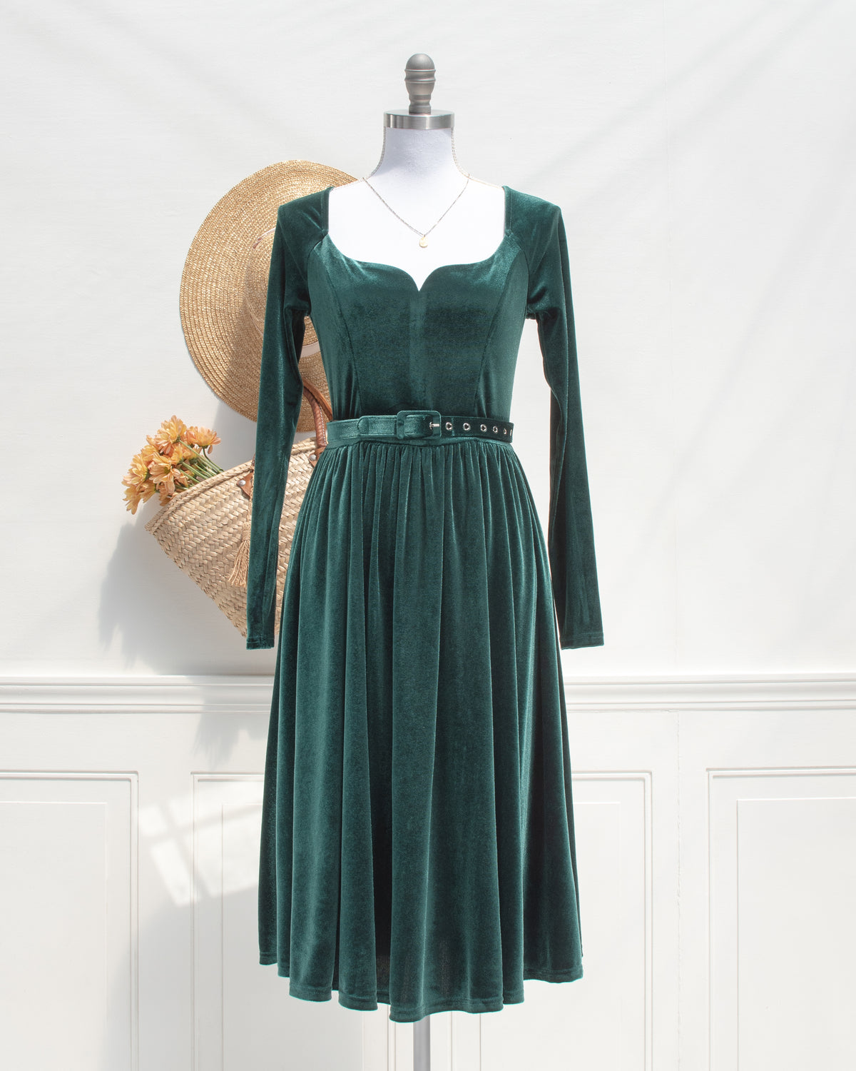 Front view of the Veronica dress, a romantic emerald velvet midi dress with a sweetheart neckline, belt and gathered skirt.