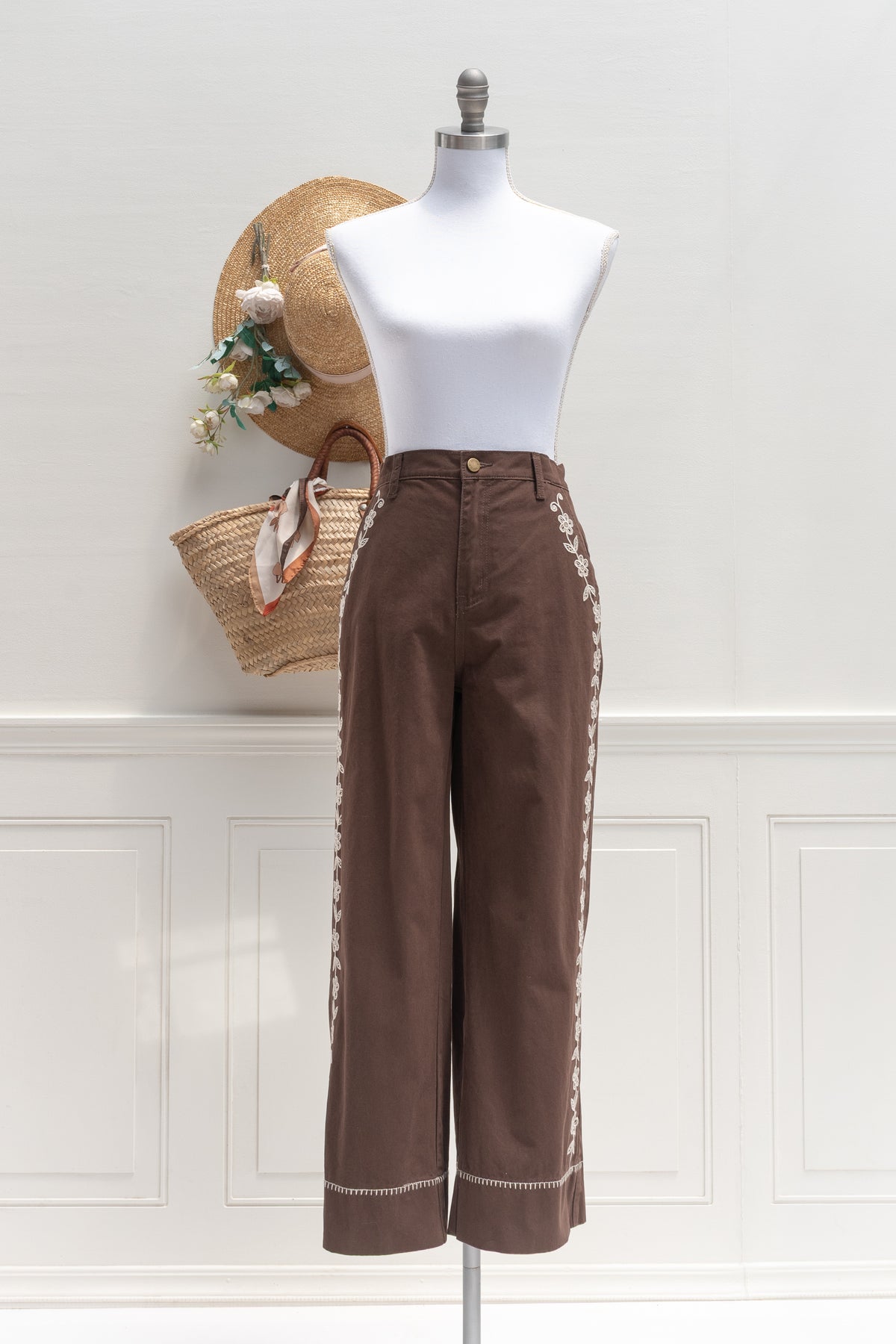 Brown cotton denim pants with floral embroidery, a wardrobe staple shown on a mannequin, front view.