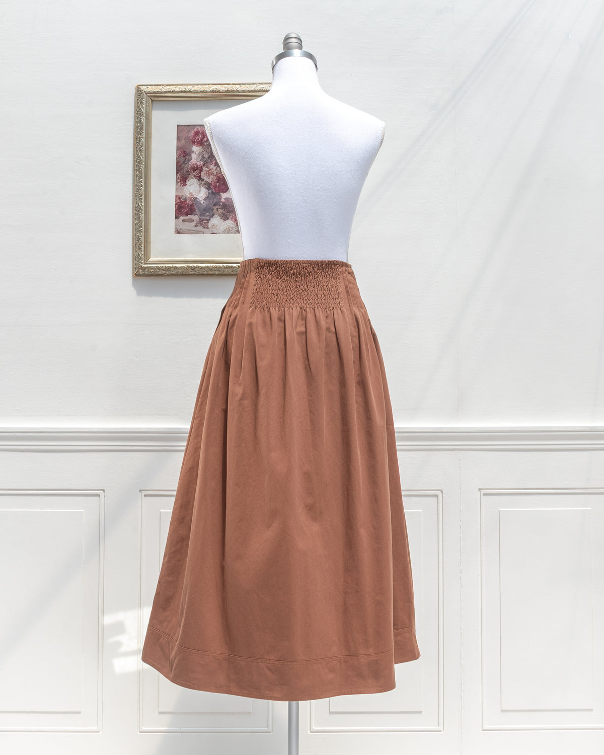 Brown cotton midi skirt with smocked back waist, mannequin back view.
