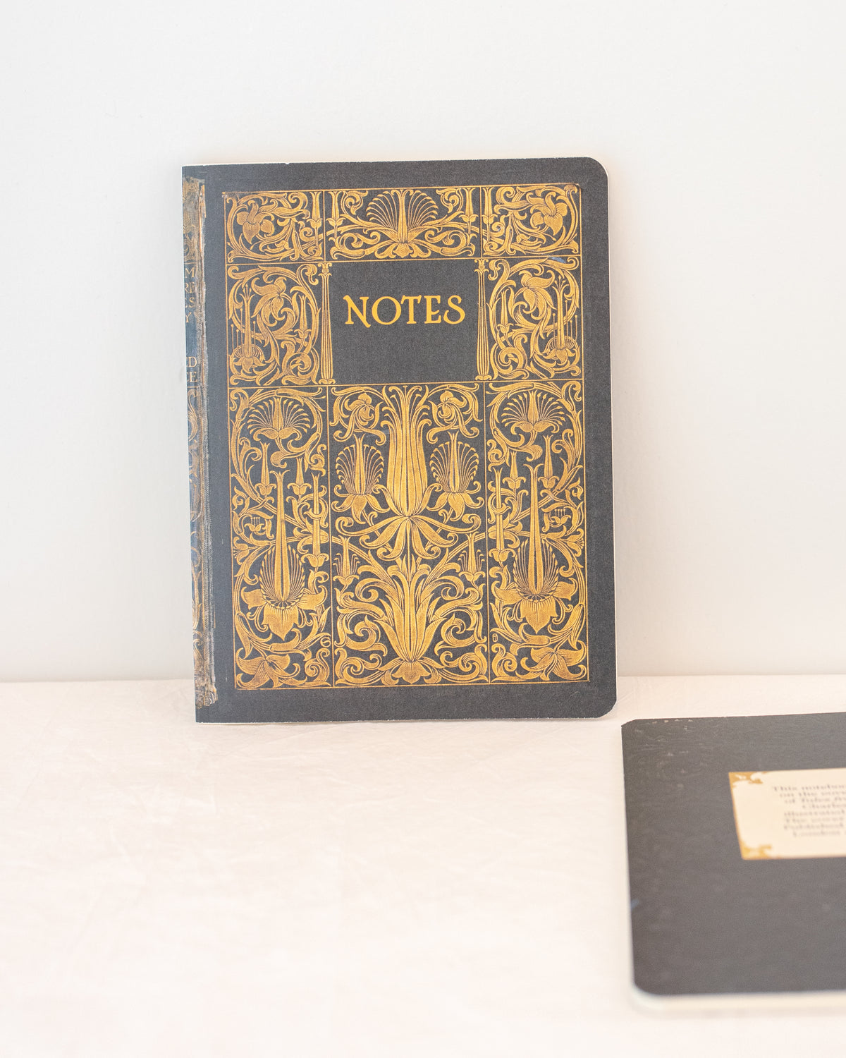 Brown and gold vintage notebook with an ornate floral cover and the word Notes, styled upright, front view.