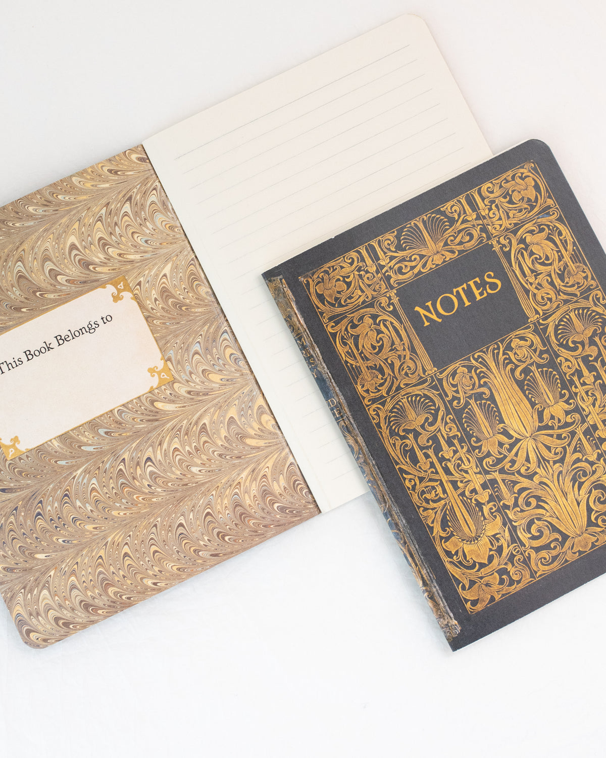 Open brown and gold vintage notebook showing marbled endpaper, a name label, and lined pages, flat lay view.