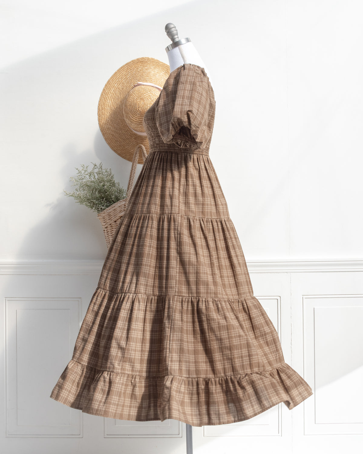 Brown plaid cotton midi dress with tiered skirt and ruffled hem on a mannequin, romantic style, side view.