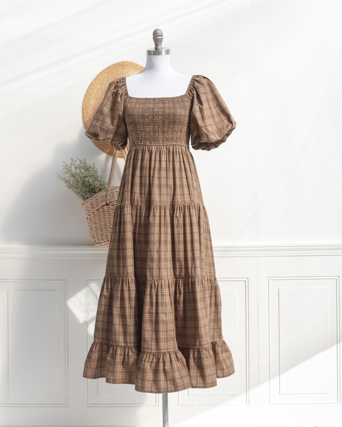 Brown plaid cotton midi dress with smocked bodice and puff sleeves on a mannequin, romantic French girl style, front view.