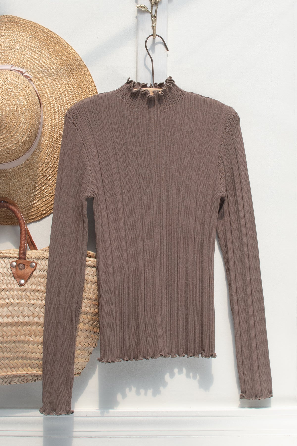 Brown ribbed knit top with a lettuce-edge mock neck, a wardrobe staple displayed on a hanger, front view.