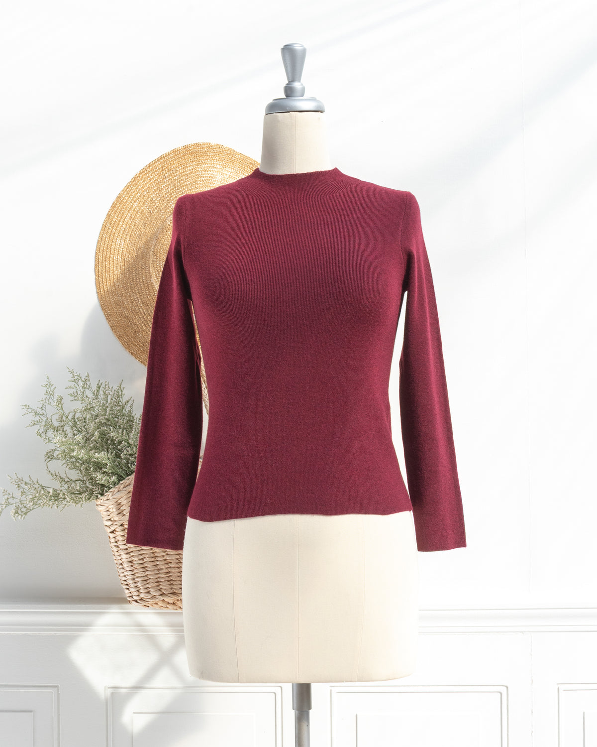 Burgundy knit top with mock neck and long sleeves on a mannequin, French girl style, front view.