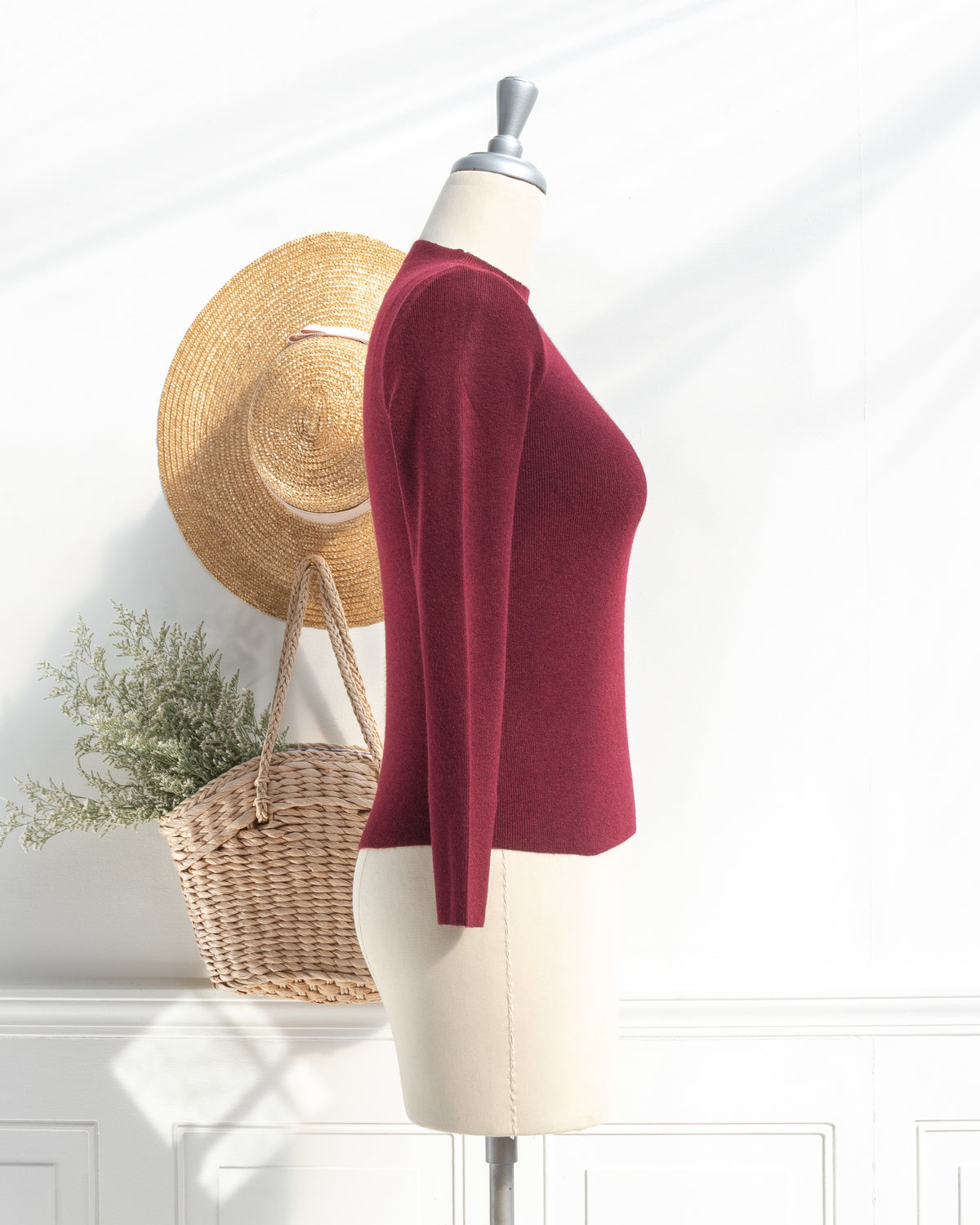 Burgundy lightweight knit top with mock neck and long sleeves on a mannequin, feminine style, side view.