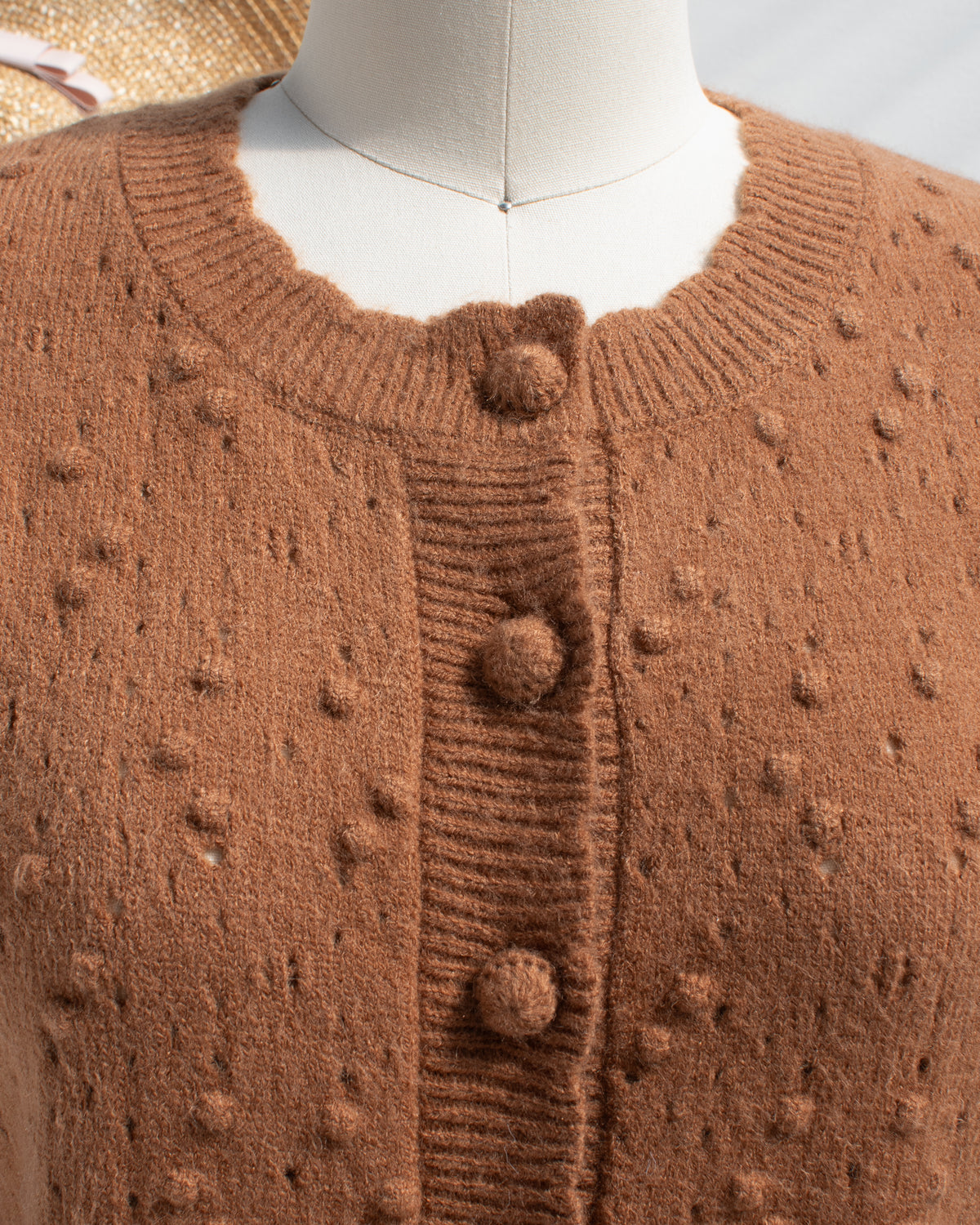Caramel pointelle cardigan with covered button detail, close mannequin view.