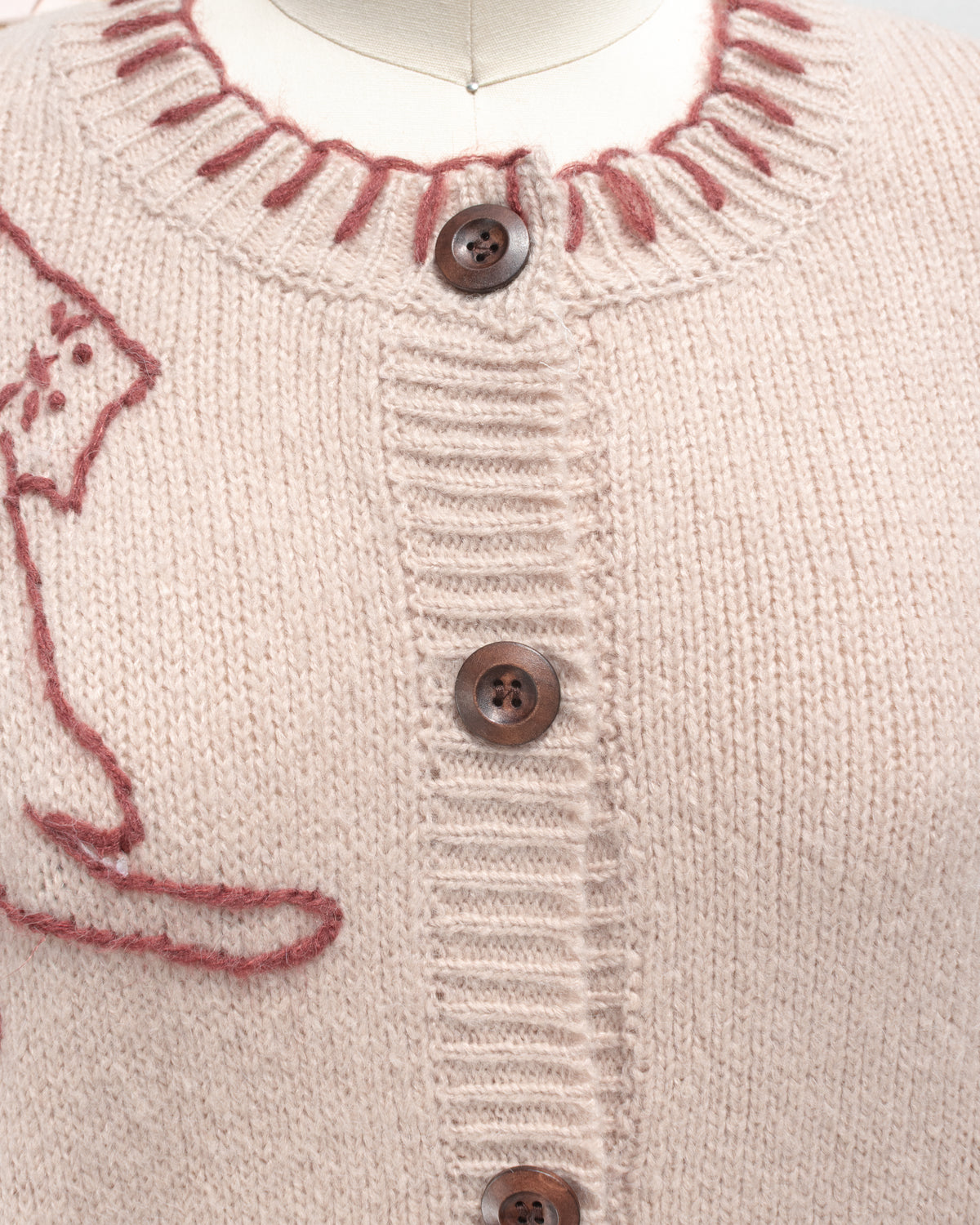 Blush knit cardigan with wood tone buttons and whipstitched collar, close detail view.