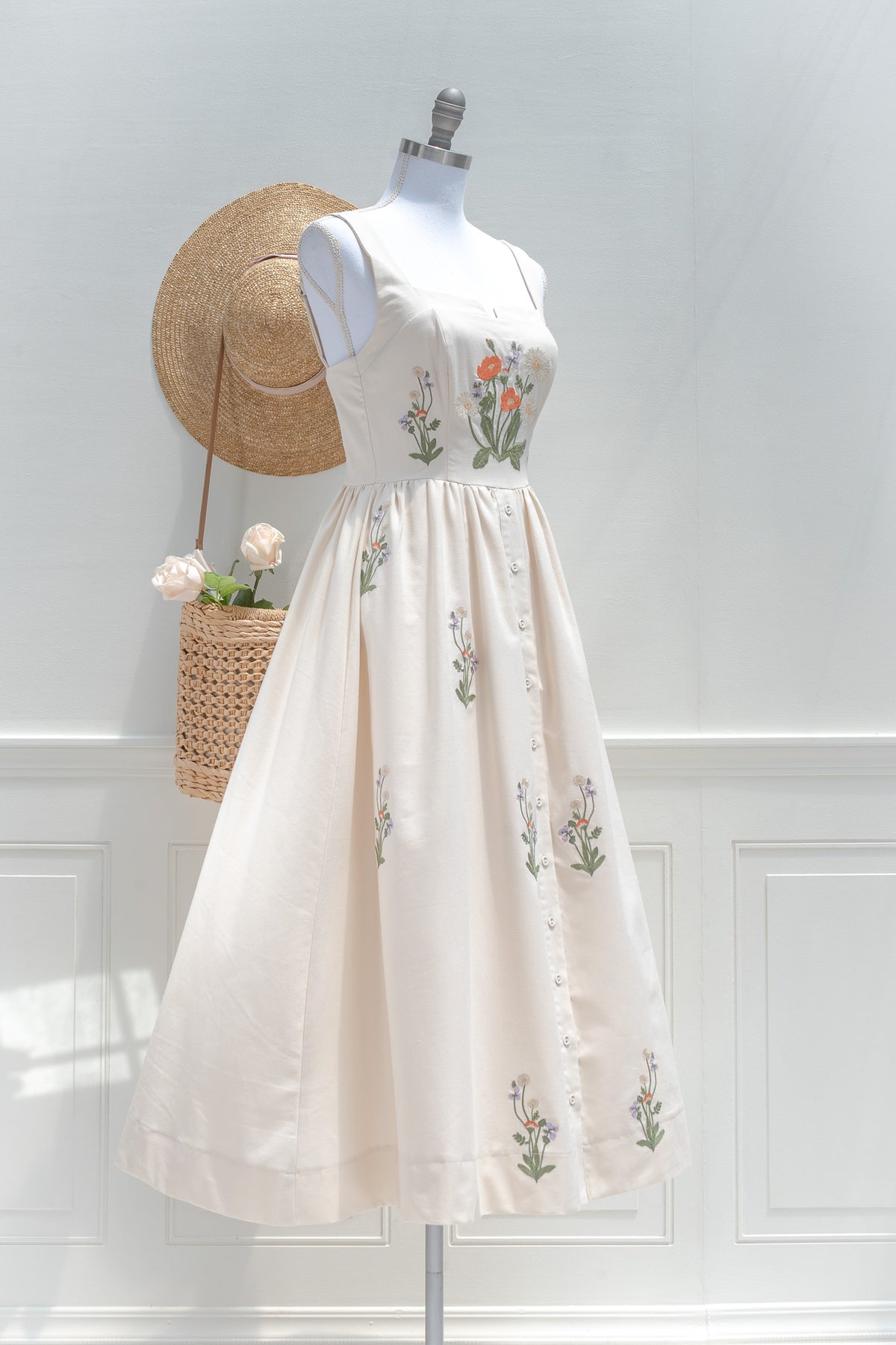 Cream cotton midi dress with floral embroidery and button front skirt three quarter view.