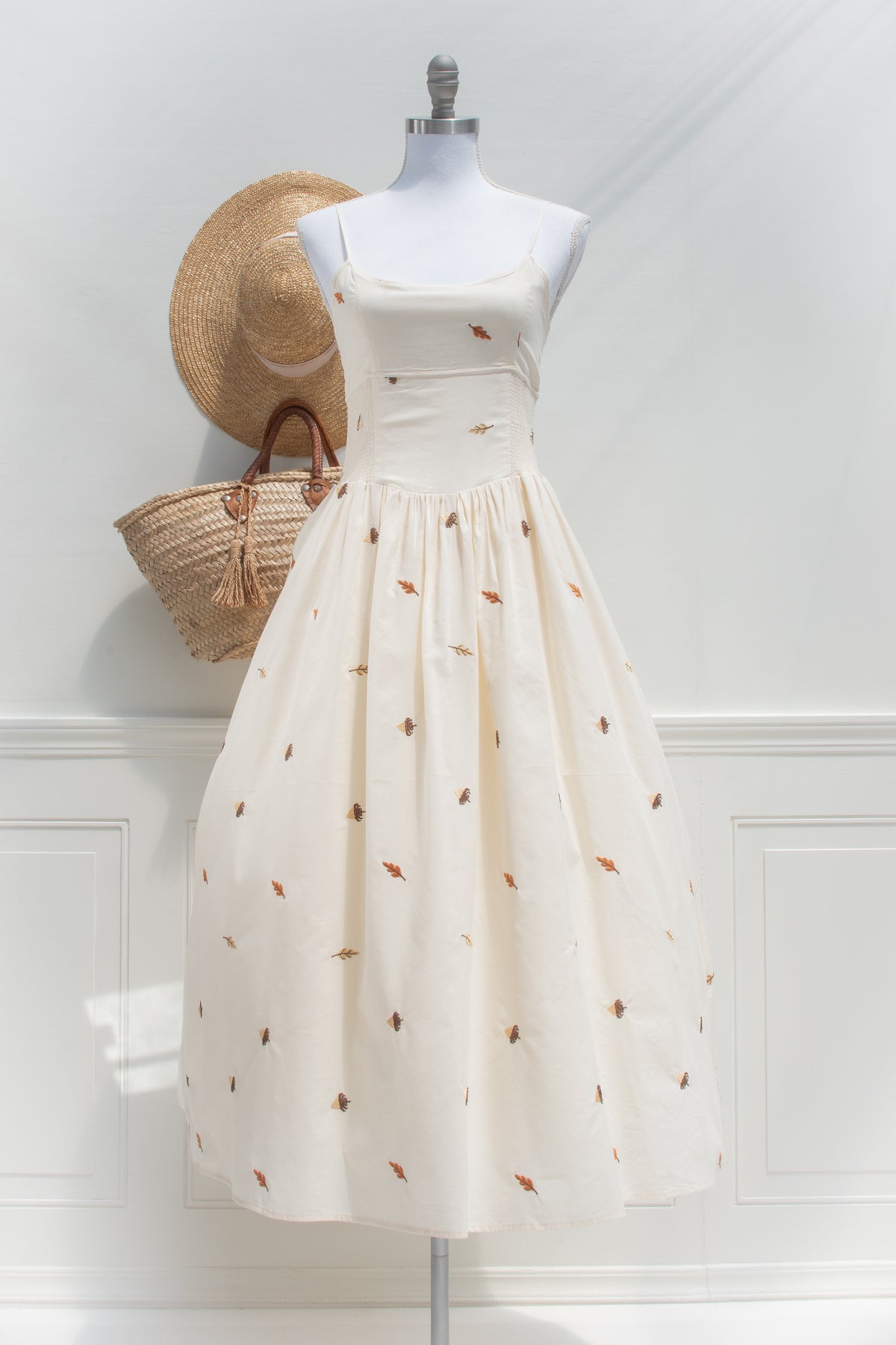Cream cotton midi dress with embroidered autumn leaves shown on a mannequin, front view.