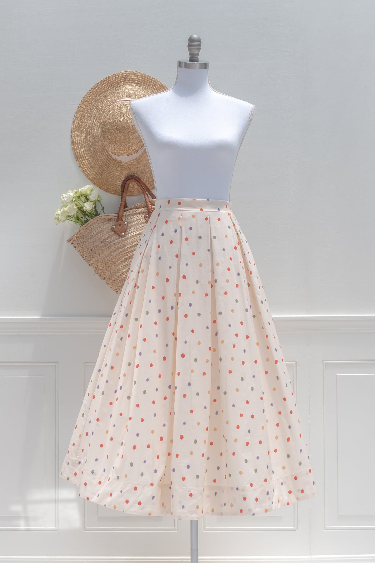 Cream cotton polka dot midi skirt with a pleated waist, shown on a mannequin, front view.