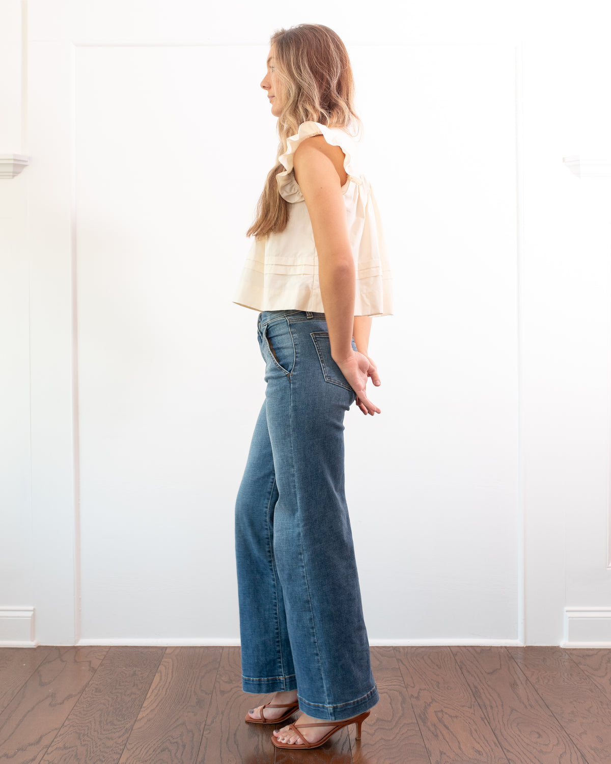 Cream cotton flutter sleeve top, classic cropped fit styled with wide leg jeans and heels, full length side view.