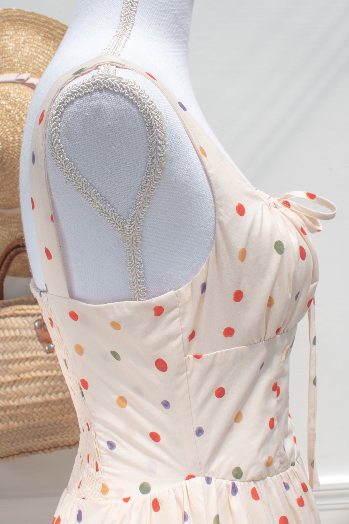Cream cotton fabric with multicolored polka dot print close up.