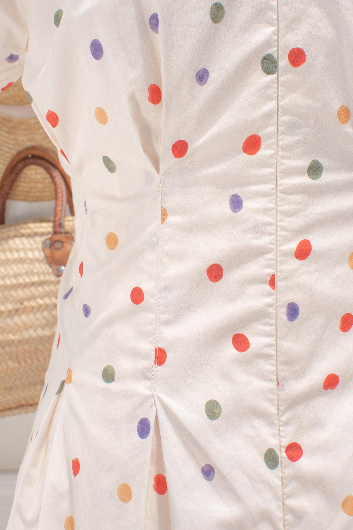 Cream cotton fabric with multicolored polka dot print close up.