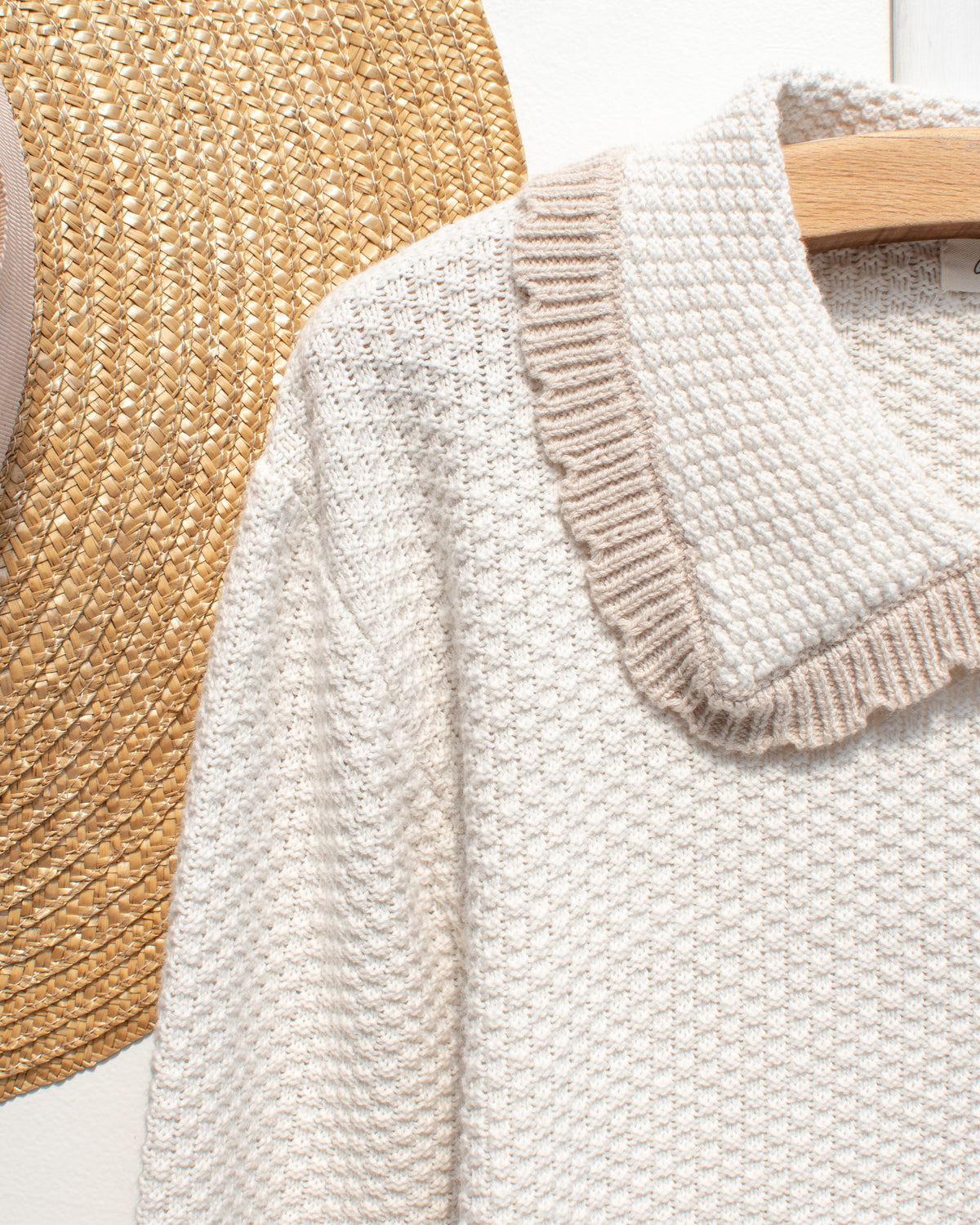 Ivory knit cardigan with tan scalloped collar, close hanger view.