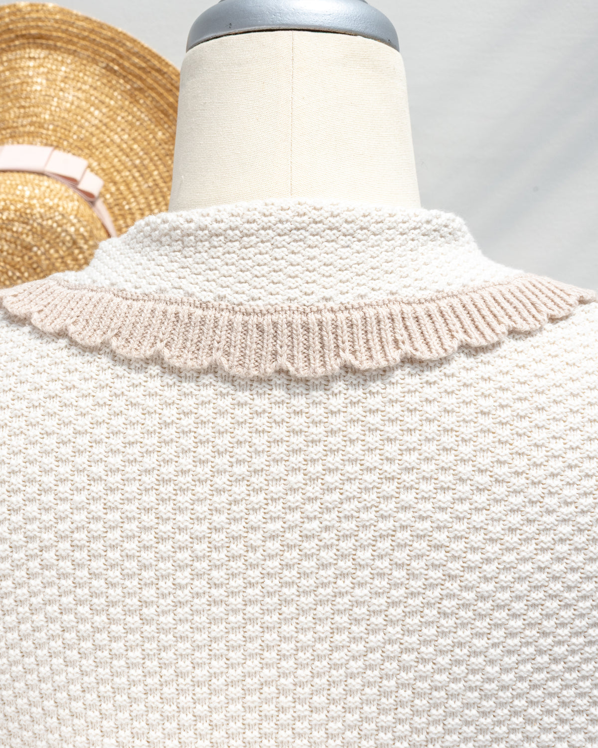 Ivory knit cardigan with scalloped collar trim at the back, close mannequin view.