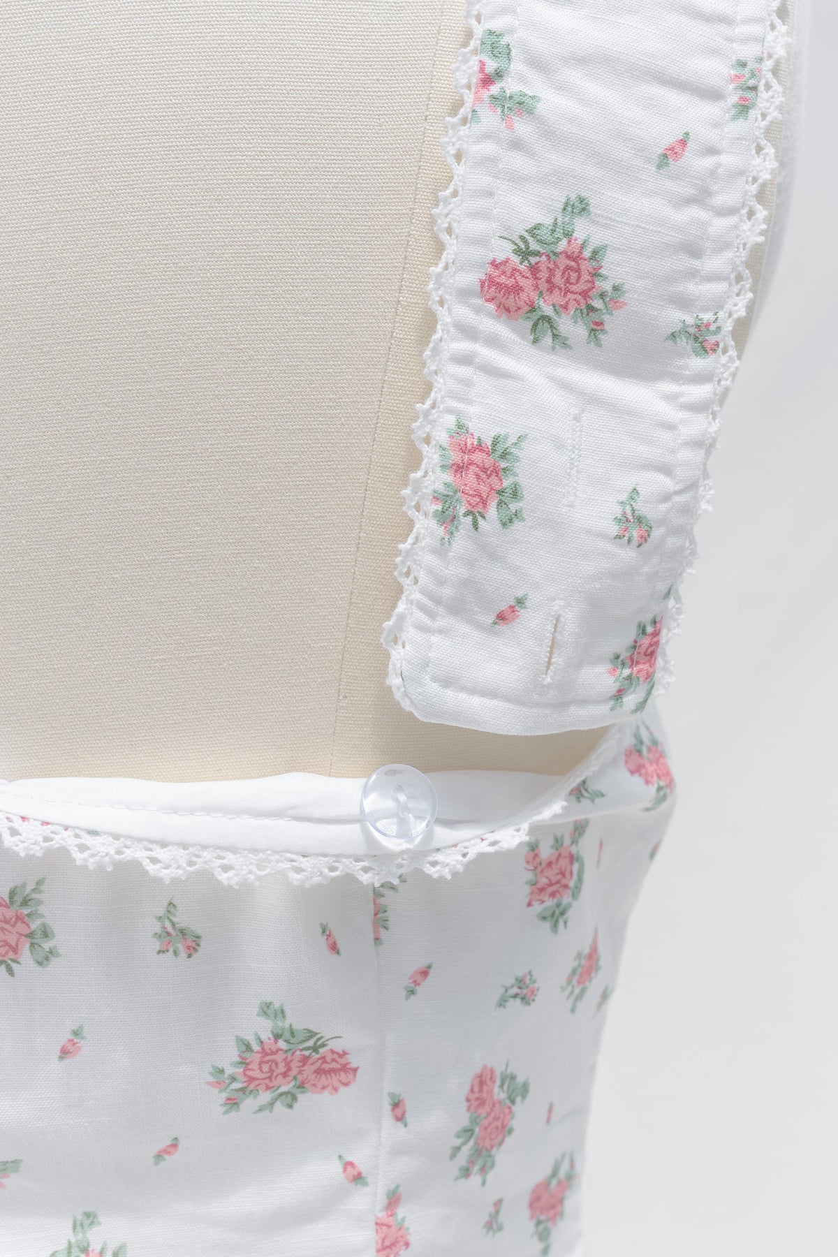 Close up of lace trimmed ruched strap and sweetheart neckline on white floral linen cotton bustier top.