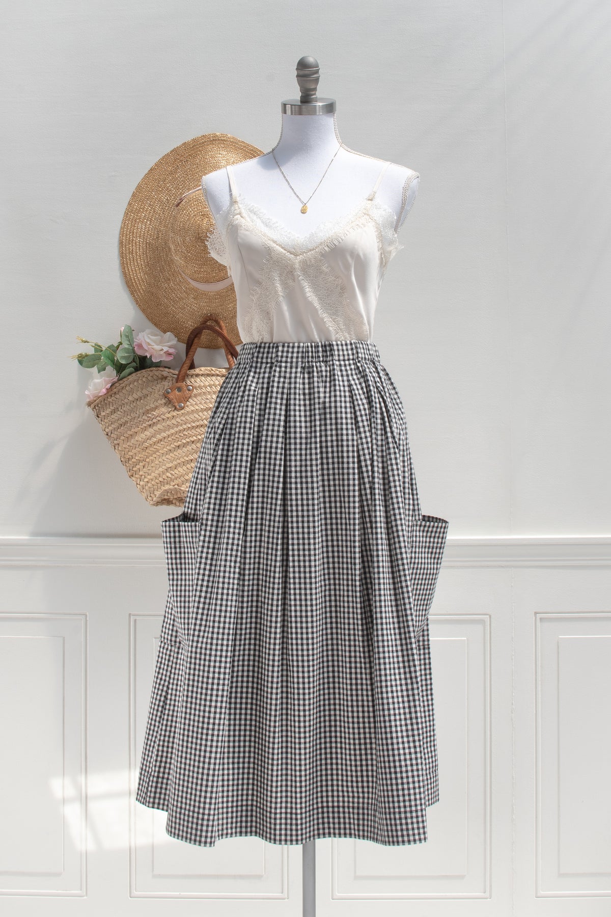 feminine french style outfit consisting of a beige camisole and gingham black and white skirt with cargo pockets. front view.