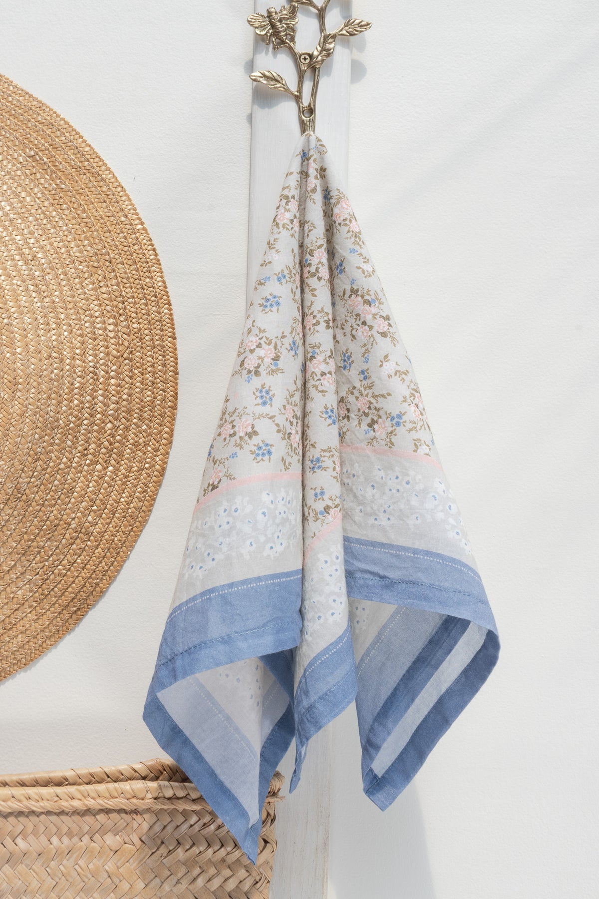 Gray cotton scarf with pink and blue floral print hanging on a hook, front view.