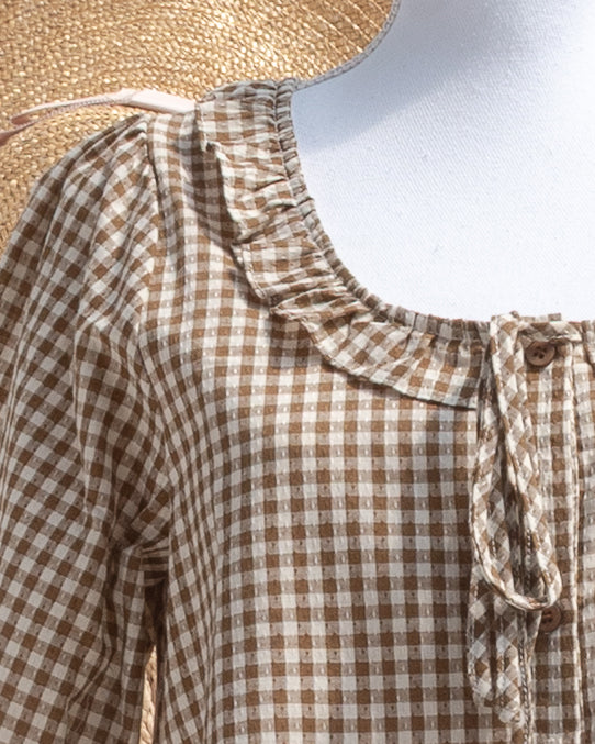 Brown gingham mini dress with ruffle collar and tie front, close mannequin view.