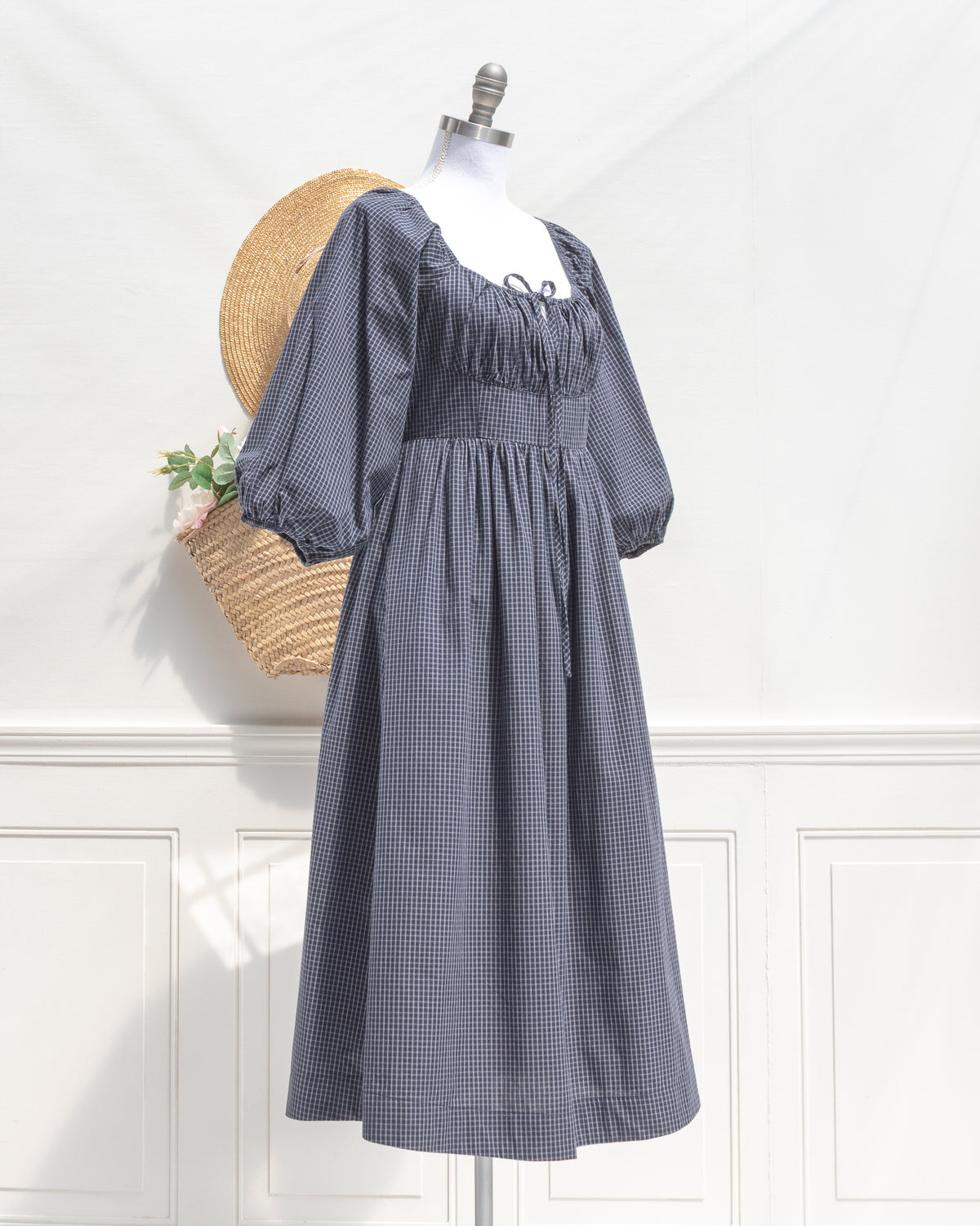 Navy check cotton midi dress with tie neckline and full skirt, a feminine fall look, mannequin three quarter view.