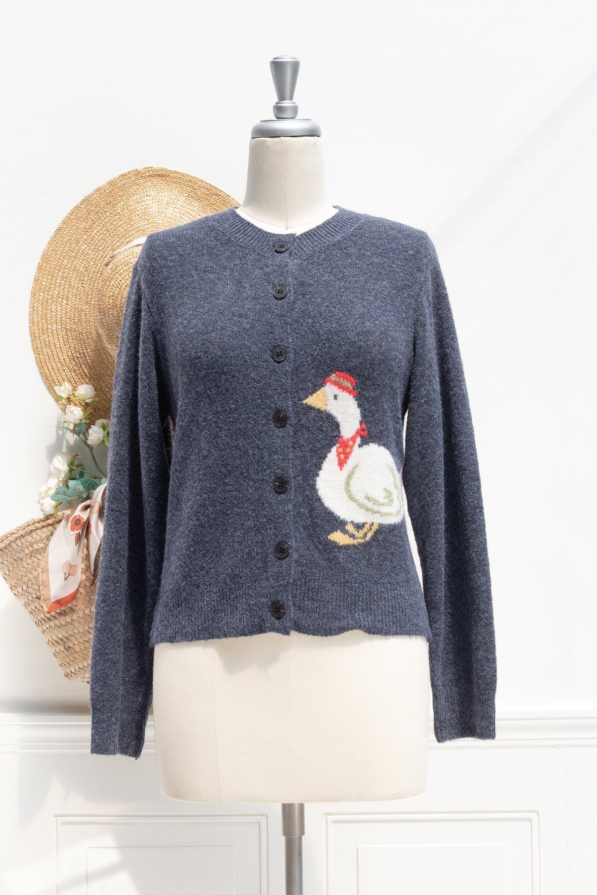 Navy knit cardigan with a goose motif, a French girl essential shown on a mannequin, front view.