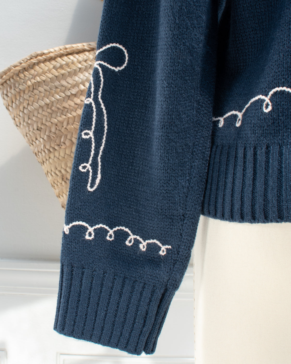 Feminine style cardigan. French girl style. Blue cardigan with whimsical bow detail embroidery. Up close sleeve view. Amantine