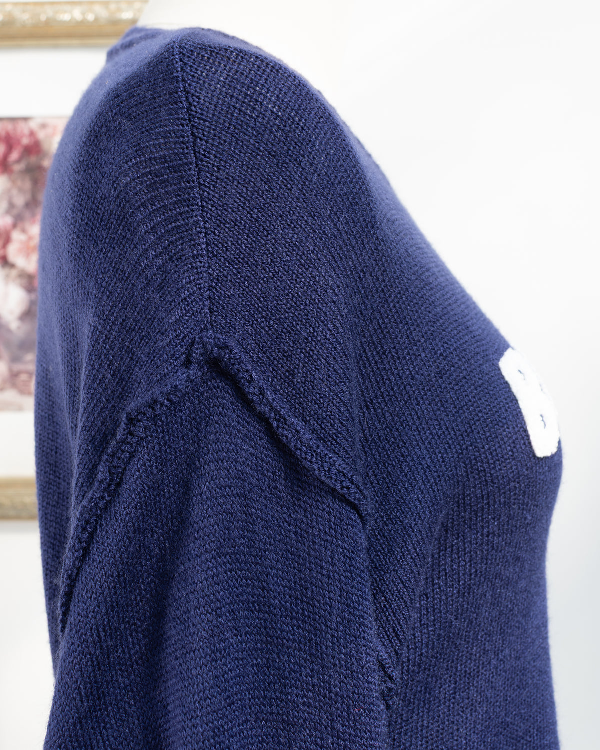 Navy knit sweater with exposed seam at the drop shoulder and sleeve, shoulder detail view.