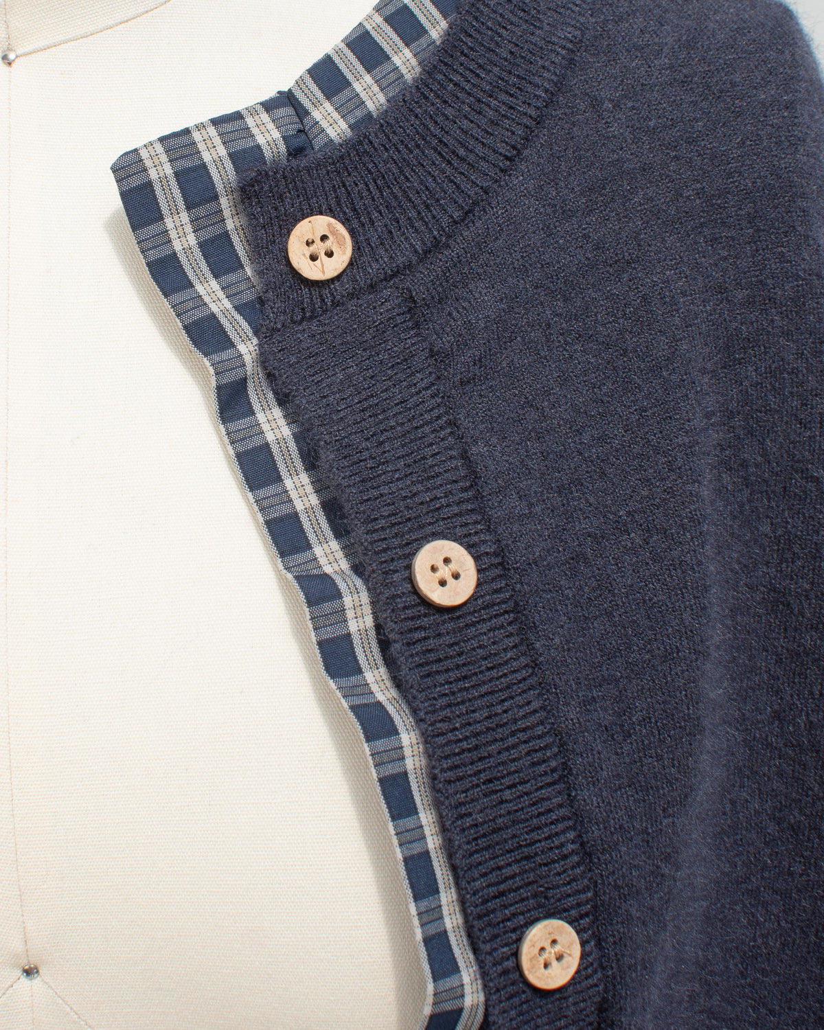 Navy knit cropped cardigan with plaid trim and wood tone buttons, close mannequin view.