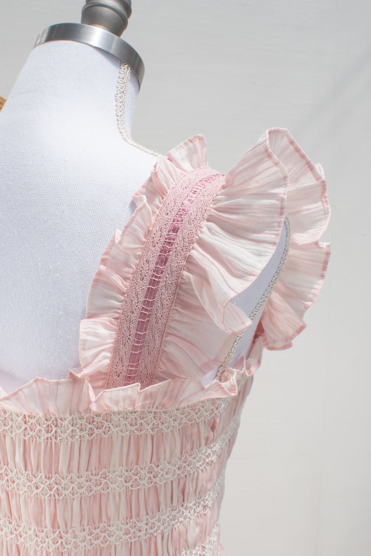 Pink chemise dress flutter sleeve and smocked bodice shown in close detail.