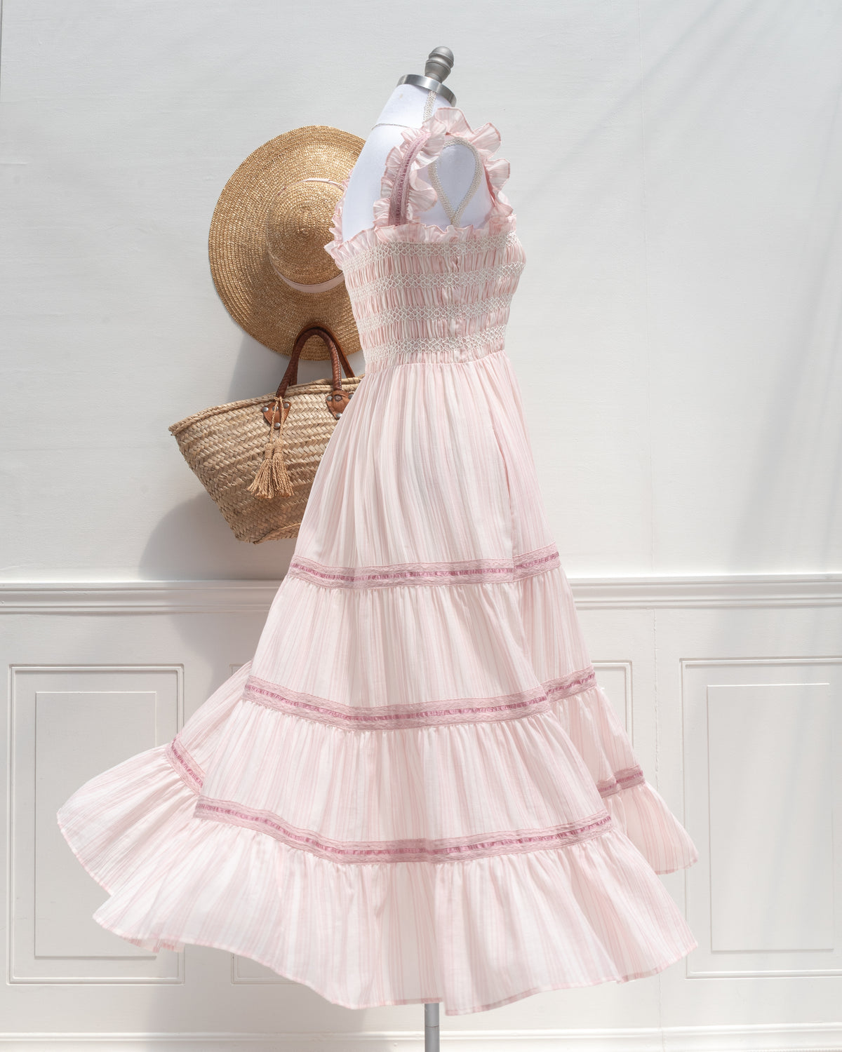 Blush pink striped midi dress with ruffle straps and ribbon tiers on a mannequin, French girl style, three quarter view.