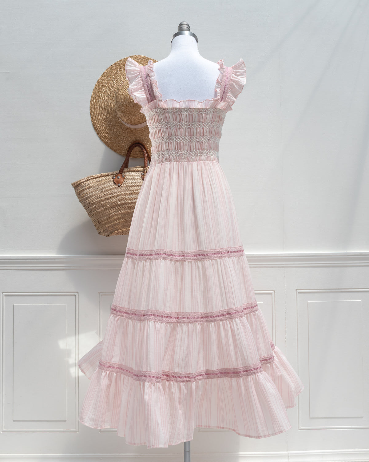 Blush pink striped midi dress with tiered ribbon panels on a mannequin, romantic French girl style, back view.