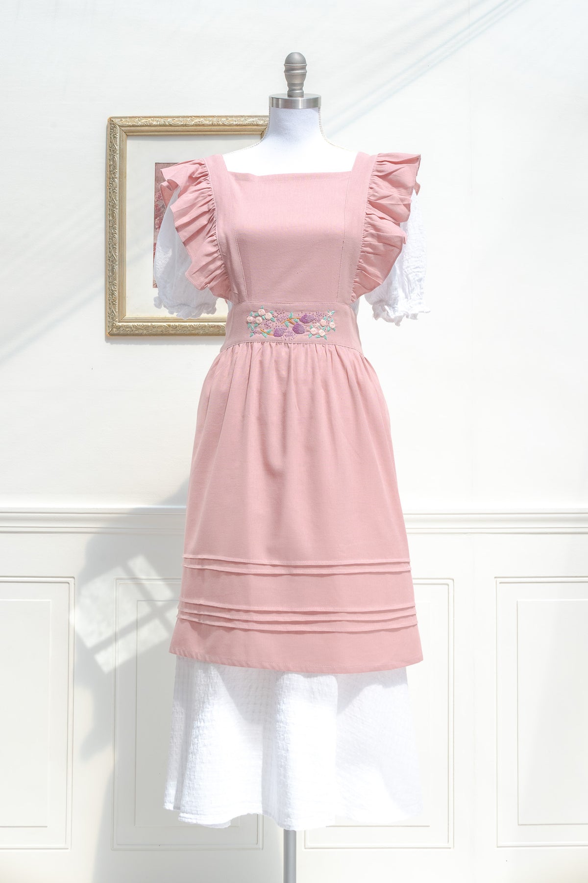 Pink ruffle apron with square neckline and gathered skirt, front view.