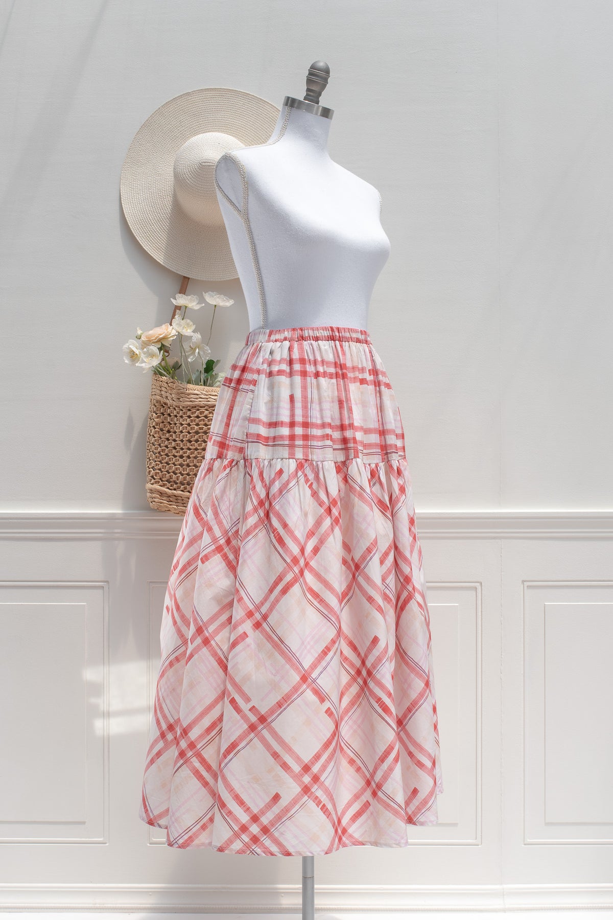 Red and pink plaid cotton midi skirt with elastic waist and tiered skirt, three quarter view.