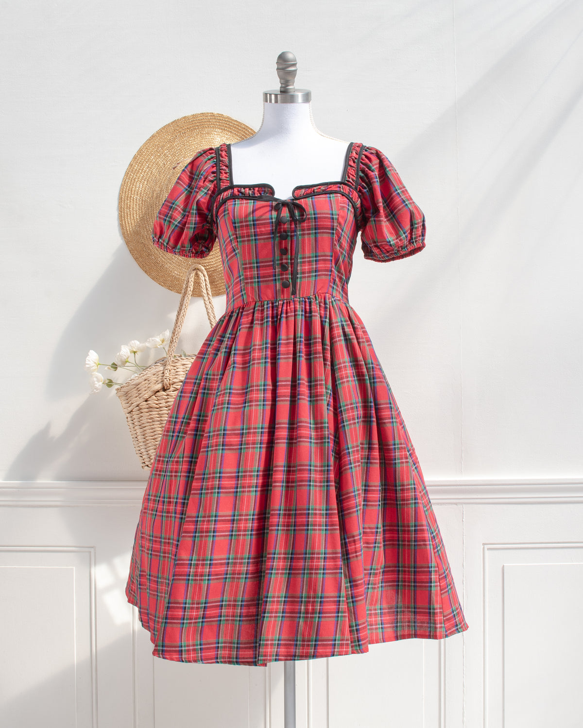 Red plaid cotton midi dress with puff sleeves and black piping, French girl style, styled on a mannequin, front view.
