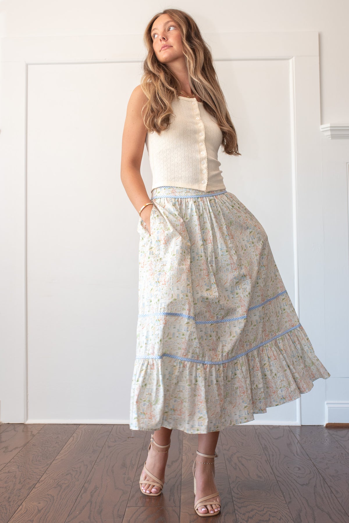 Cream retro village print cotton midi skirt styled with ribbed tank top, front view on model.
