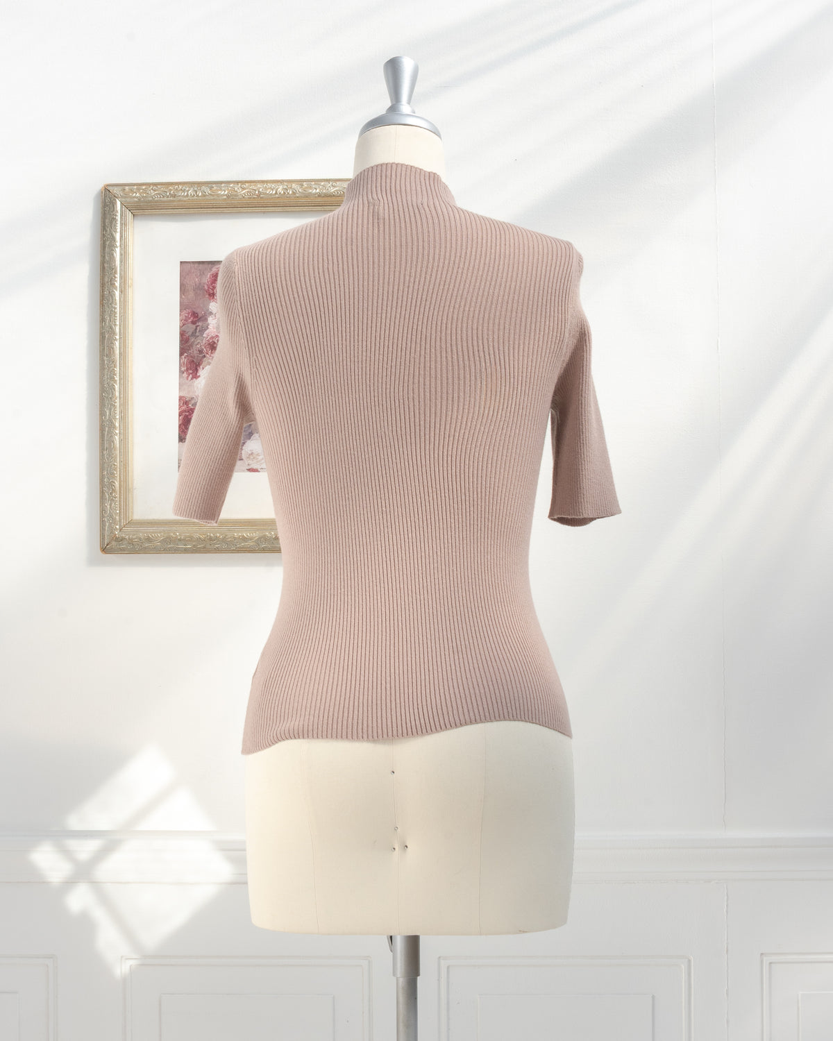 Taupe ribbed knit top with stretchy fit and mock neck on a mannequin, back view.