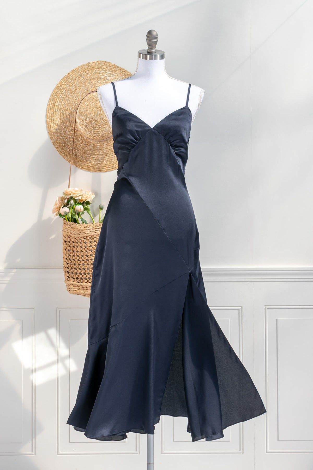 Beautiful wedding guest and formal dress in navy blue. French style feminine and romantic dress with straps, slit, and a bow. Front view. Amantine dresses.