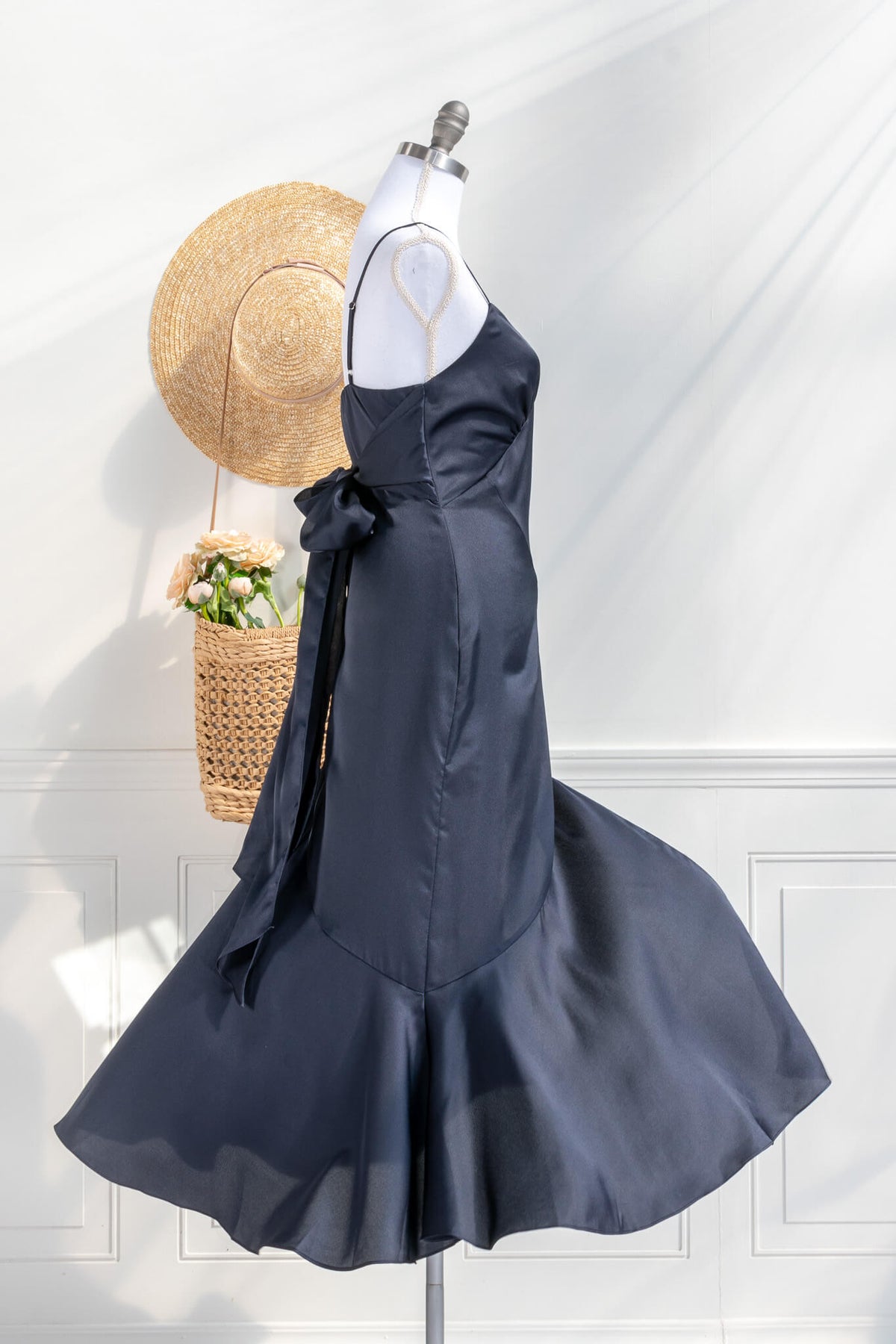 Beautiful wedding guest and formal dress in navy blue. French style feminine and romantic dress with straps, slit, and a bow. Front view. Amantine dresses.
