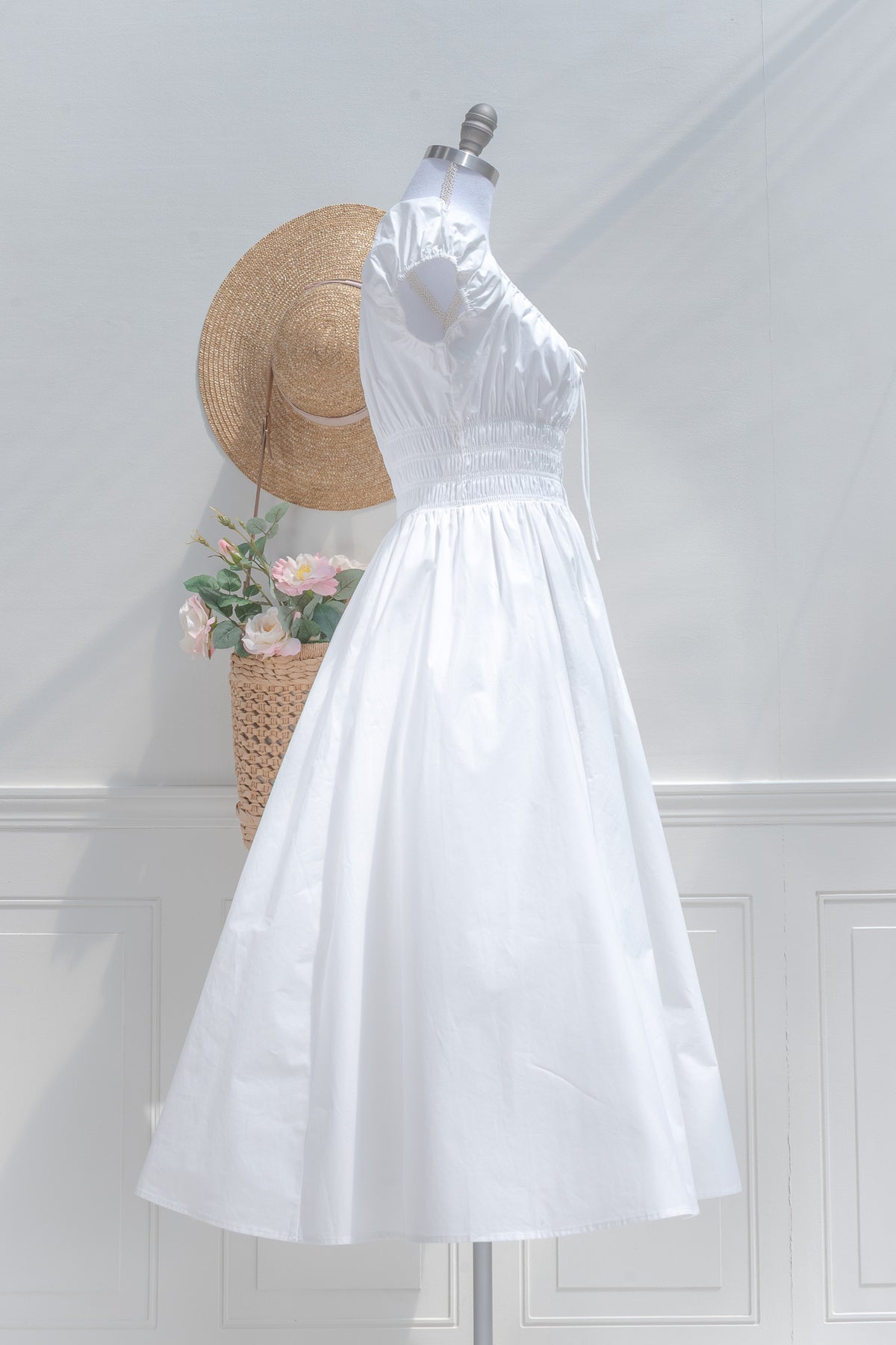 White cotton chemise midi dress worn off shoulder showing gathered sleeve and smocked bodice, side view.