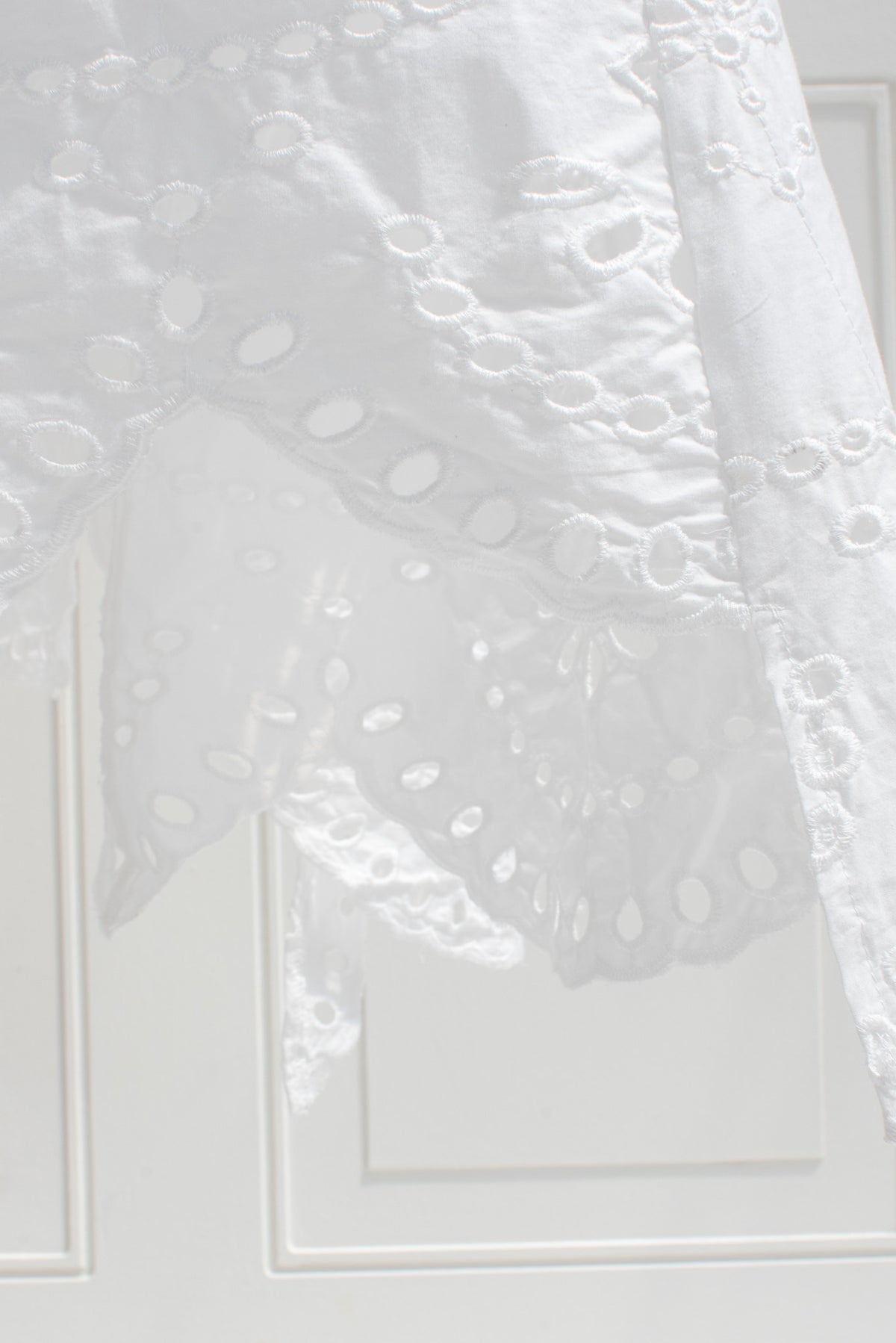 White cotton eyelet fabric and cutwork embroidery detail close up.
