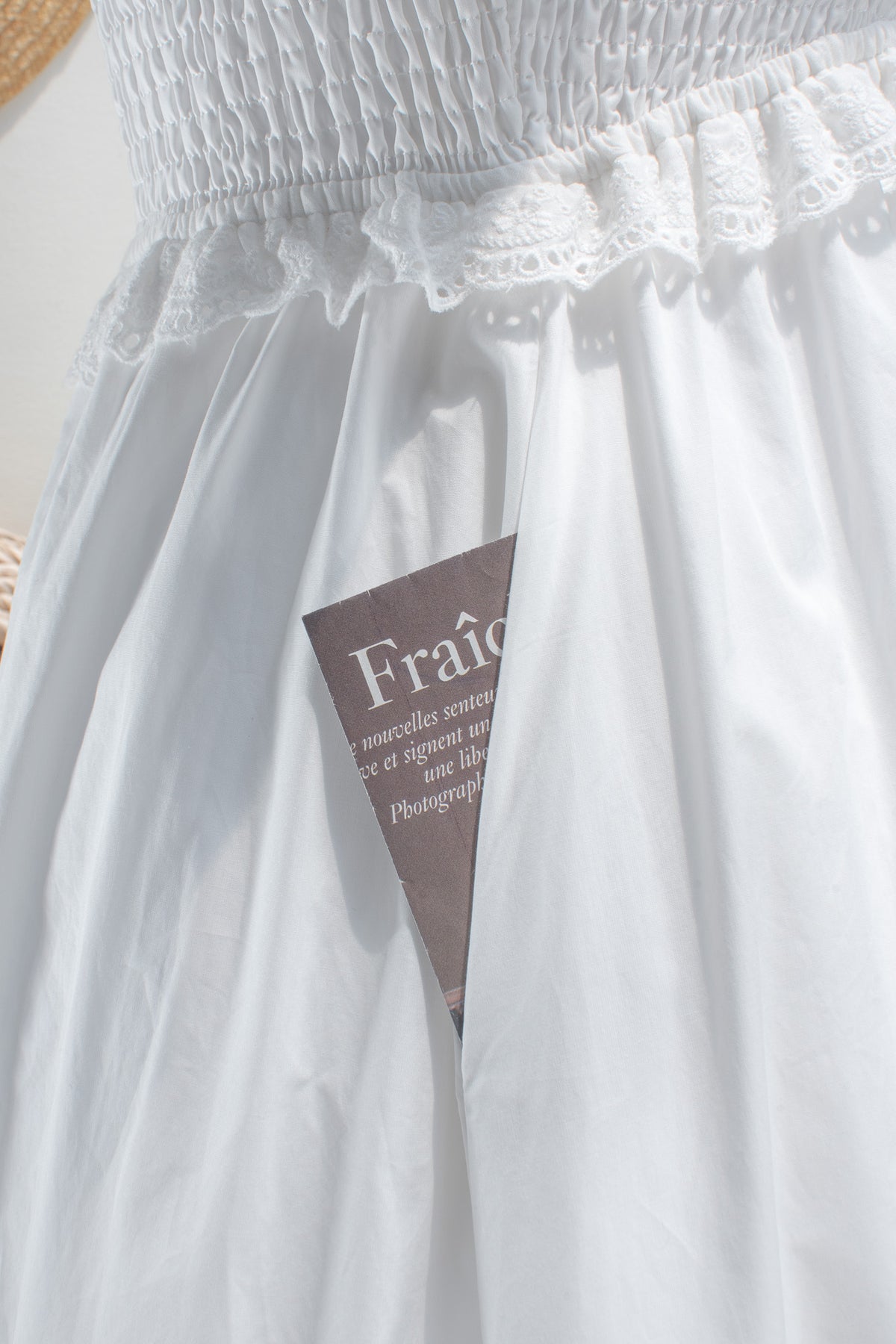White cotton midi dress with eyelet lace waist trim and side pocket detail.