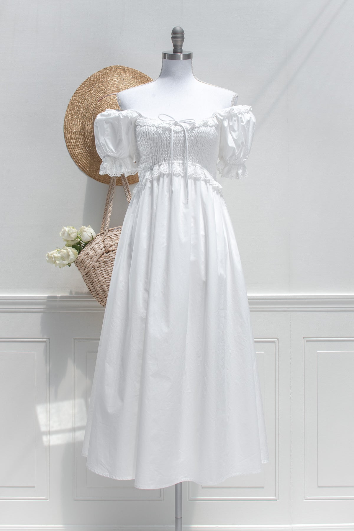 White cotton midi dress styled off shoulder with smocked bodice, front view.