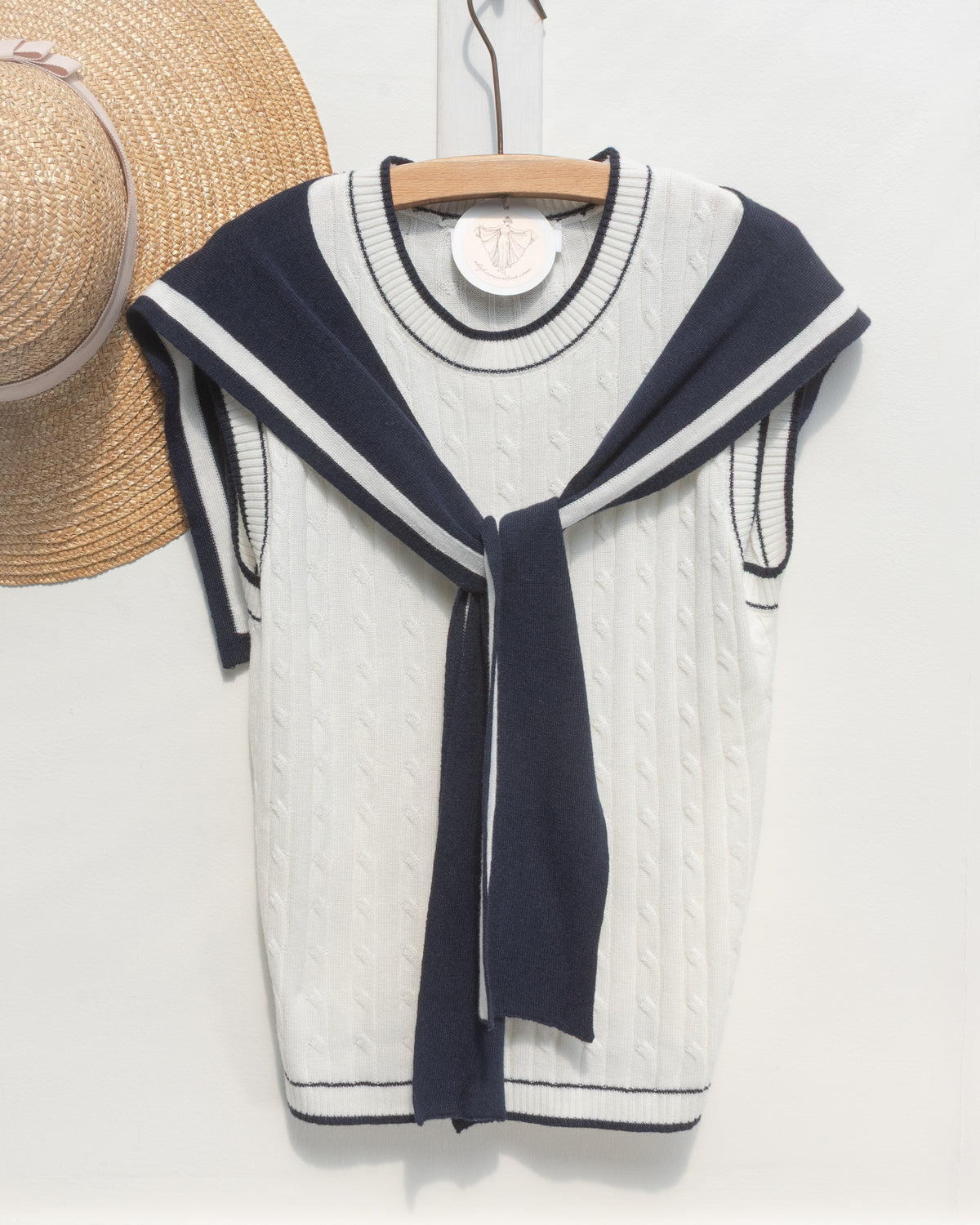White cable knit sailor top with navy collar, a French girl essential, shown on a hanger, front view.
