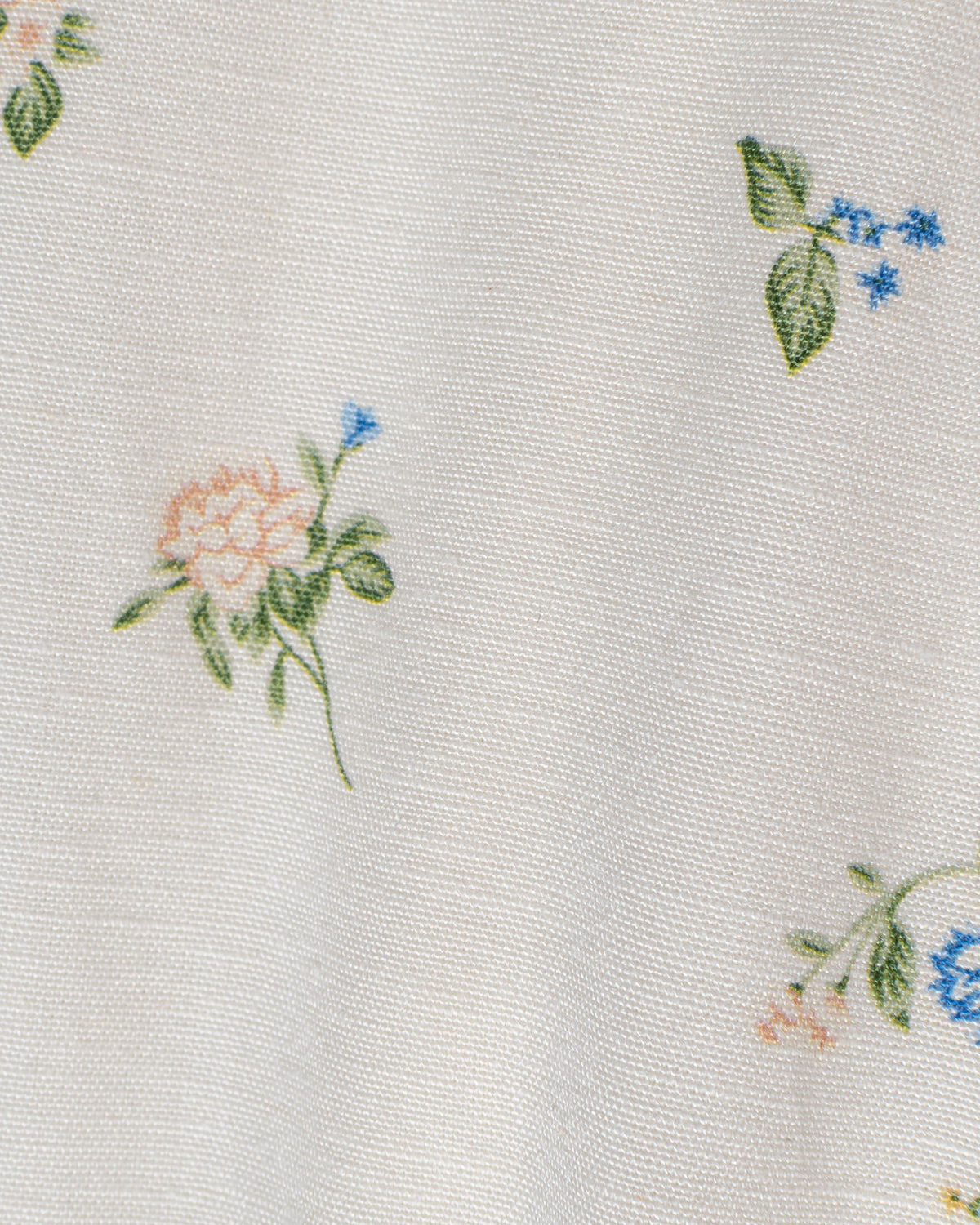 Close-up of a delicate blue floral motif with floral blooms on cream linen-blend fabric.