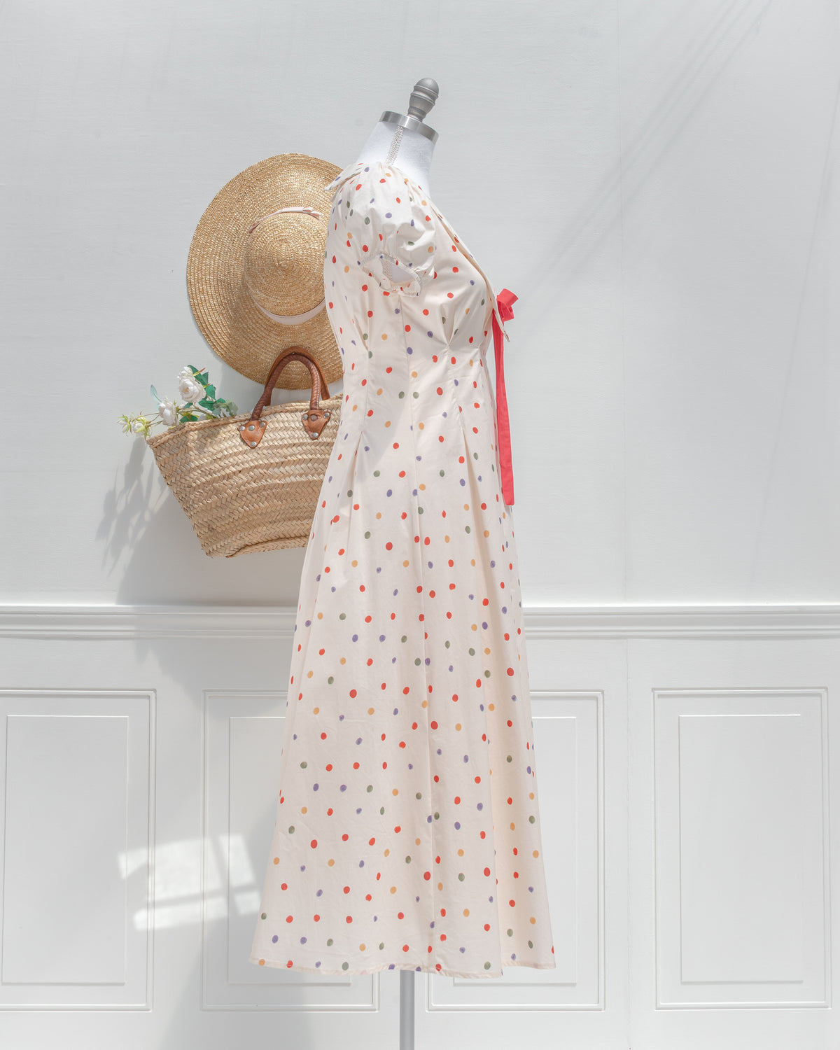 Side view of the cream polka dot dress, showing the puff sleeve, nipped waist and flared midi skirt.